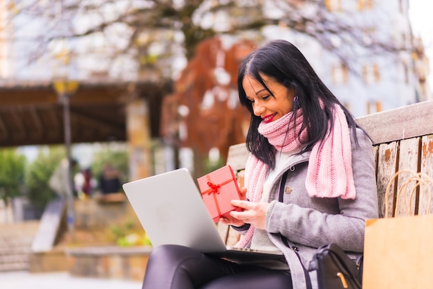 Regalo sorpresa, chica morena caucásica abriendo el regalo del novio en una videollamada con la computadora, separados por distancia