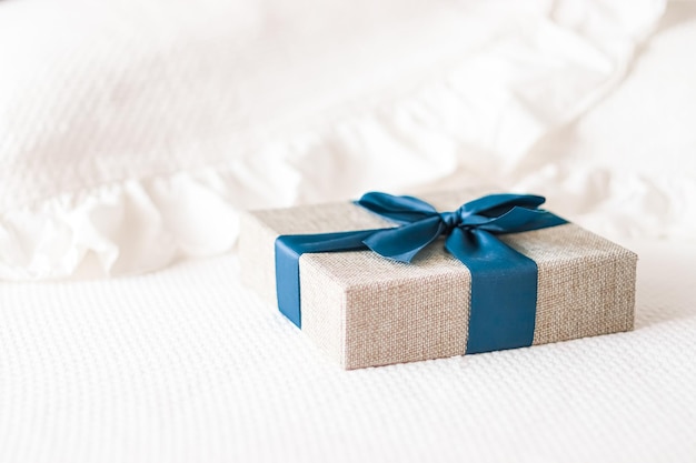 Regalo de vacaciones y entrega de compras en línea de lujo caja de regalo de lino envuelto con cinta azul en la cama en el dormitorio estilo campestre chic