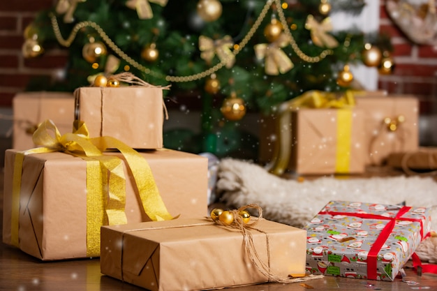 Los regalos de Año Nuevo confeccionados en diferentes cajas para toda la familia están cerca del árbol de Navidad en la habitación en invierno.