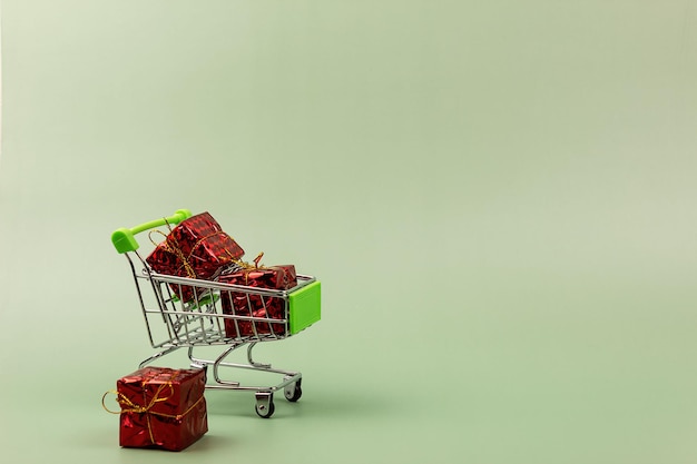 Regalos en un carrito de compras sobre un fondo verde.