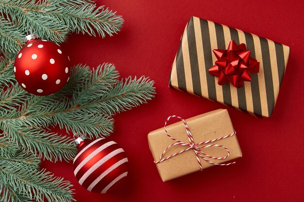 Regalos de composición de Navidad ramas de árboles de Navidad y adornos sobre fondo rojo.