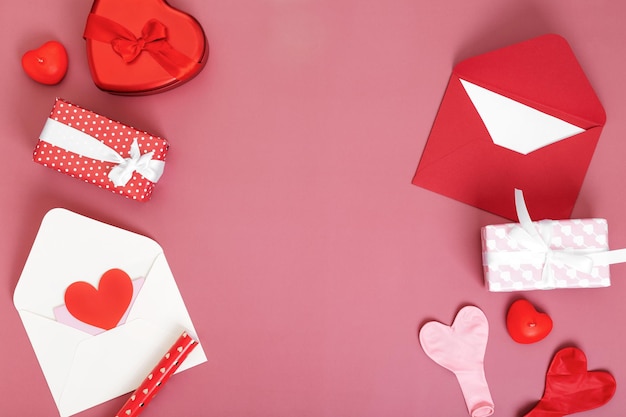 Regalos conceptuales para sus seres queridos, para el día de San Valentín, el día de la mujer, el día de la madre o el cumpleaños. Sobres blancos y rojos alrededor de cajas con globos de regalo y velas en forma de corazón. Copie el espacio. Vista superior