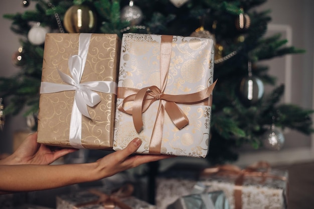 Regalos elegantes con cintas cerca de un hermoso árbol de Navidad