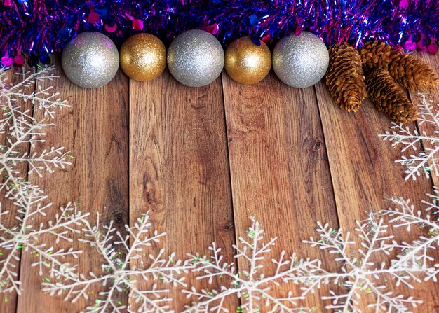 Los regalos se envasan en papel kraft y se atan con una cinta de raso con juguetes navideños y oropel morado sobre un fondo de madera Decoración para el árbol de Navidad