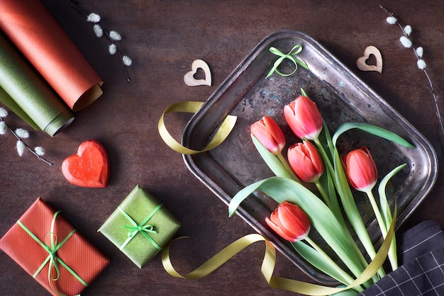 Regalos envueltos, flores de sauce y tulipán y corazones de madera.