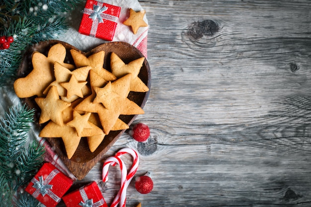 Regalos de galletas y ramas de abeto en una mesa de madera.