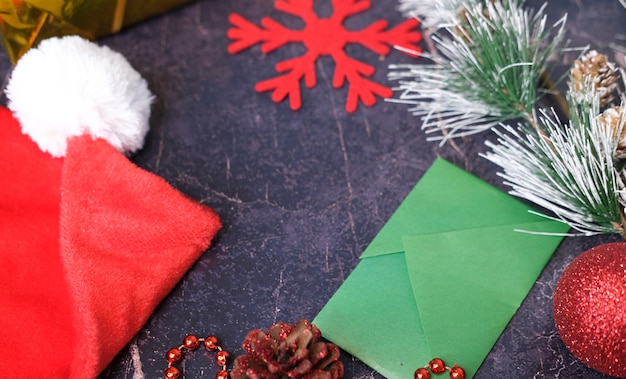 Regalos de Navidad y Año Nuevo. Enfoque selectivo. Sombrero de Papá Noel, cajas con regalos, abalorios, juguetes de Navidad sobre un fondo oscuro.