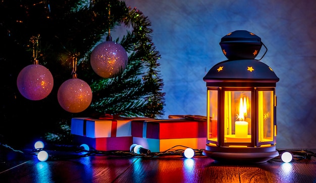 Regalos de Navidad bajo el árbol de Navidad a la luz de un farol con una vela