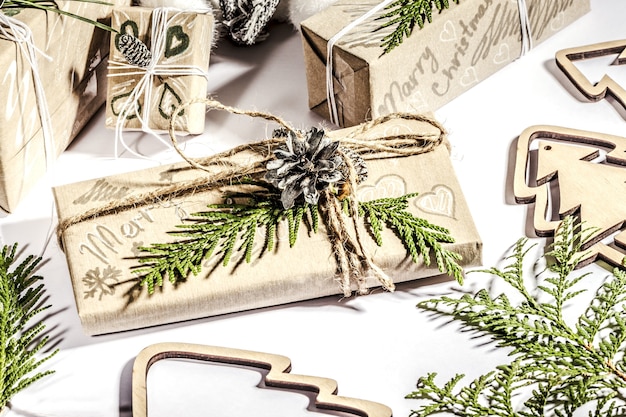 Regalos de Navidad con caja de regalo decorada con piñas y ramitas sobre fondo blanco, preparación para las vacaciones.