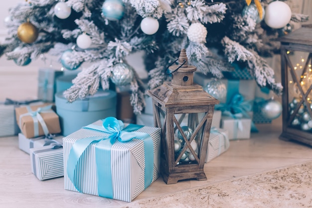 Los regalos de Navidad en cajas se encuentran cerca del árbol de Navidad decorado