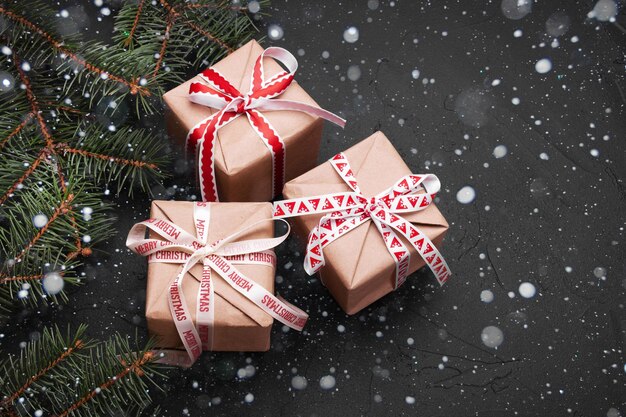 Regalos de Navidad con cinta roja sobre fondo negro con adornos festivos