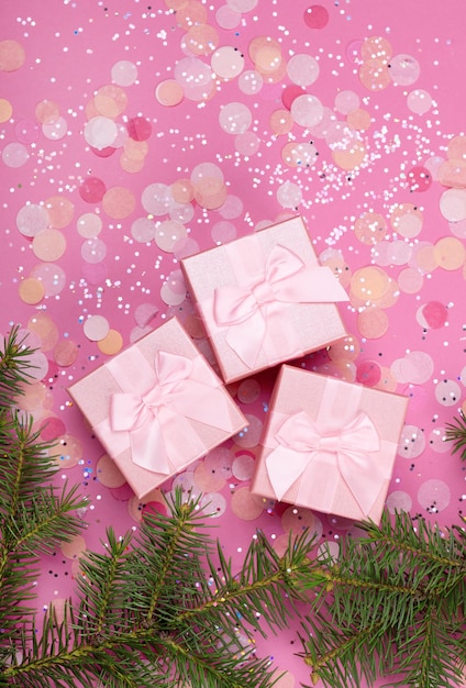 Foto regalos de navidad con cinta rosa sobre fondo rosa pastel con decoraciones festivas