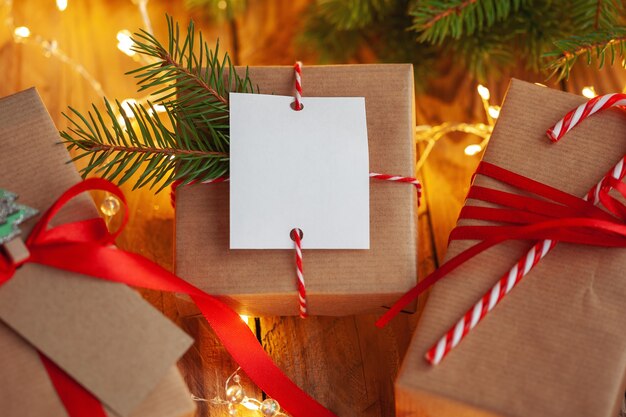 Regalos de Navidad en envases artesanales sobre una mesa de madera con el telón de fondo de un árbol de Navidad decorado.