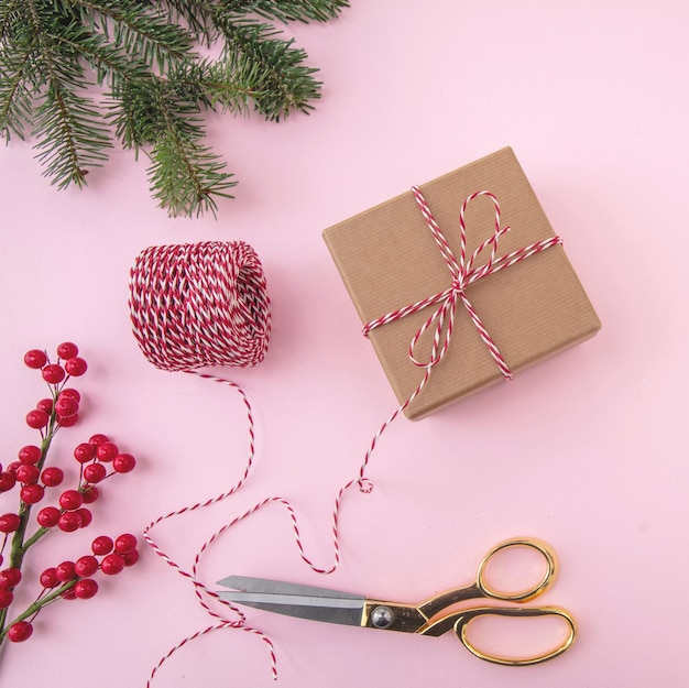 Regalos de Navidad envolviendo tijeras doradas y cinta sobre fondo de color rosa