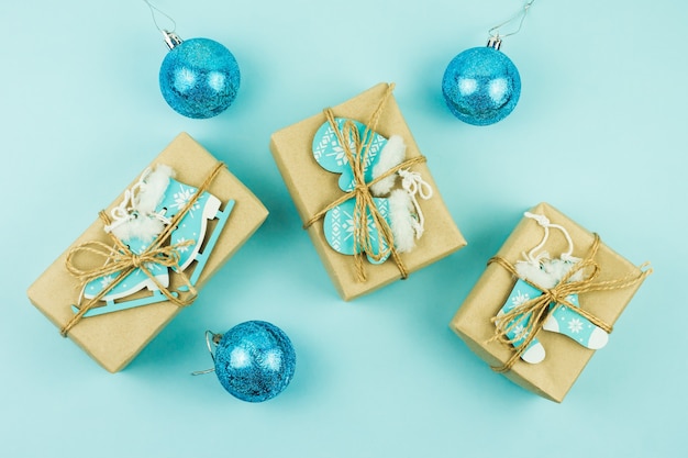 Regalos de Navidad envueltos en papel artesanal con diferentes juguetes de madera como decoración sobre fondo azul.