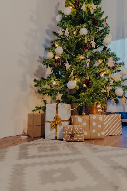 Regalos de Navidad envueltos en papel kraft bajo el árbol de Navidad.