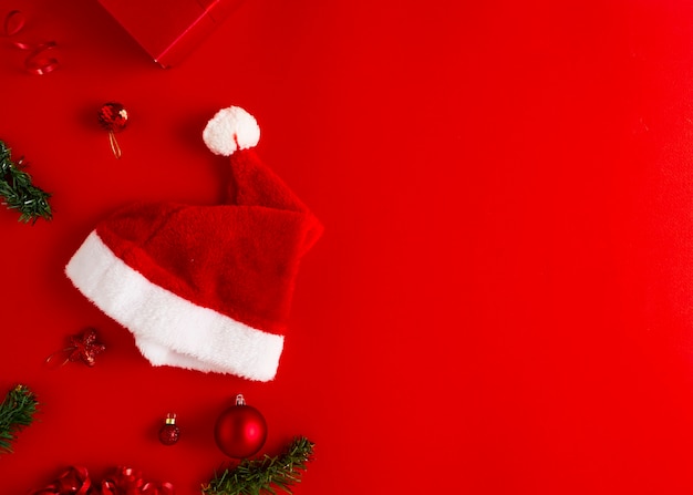 Regalos de Navidad gorro de Papá Noel con regalos y adornos navideños en un papel rojo