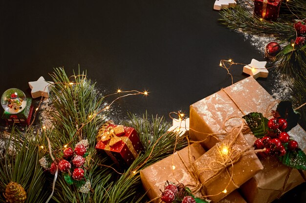 Regalos de Navidad y guirnaldas cerca de la rama de abeto verde sobre fondo negro. Fondo de Navidad. Vista superior. Copie el espacio. Naturaleza muerta. Endecha plana. Año nuevo