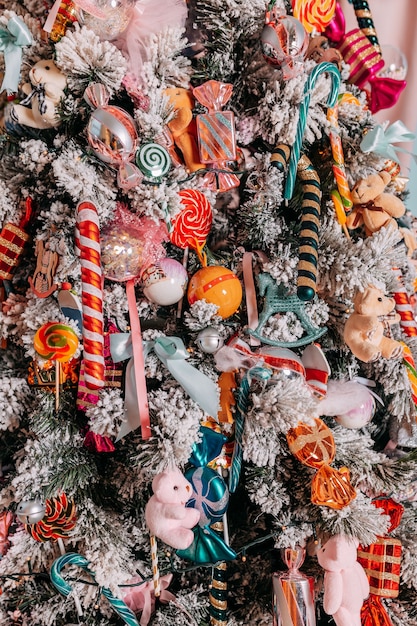 Regalos de Navidad para niños bajo el árbol. Árbol de Navidad decorado con juguetes y coloridos bastones de caramelo y dulces. Presenta cajas debajo del árbol de Navidad.