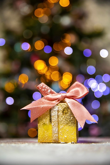 Regalos de navidad de oro con lazo rosa con fondo de luces bokeh de árbol de navidad y espacio de copia vacaciones ...
