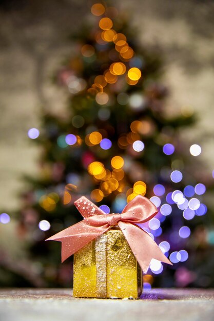 Regalos de navidad de oro con lazo rosa con fondo de luces bokeh de árbol de navidad y espacio de copia vacaciones ...