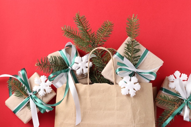 Regalos de Navidad en papel kraft con cintas verdes y blancas en bolsa de papel.