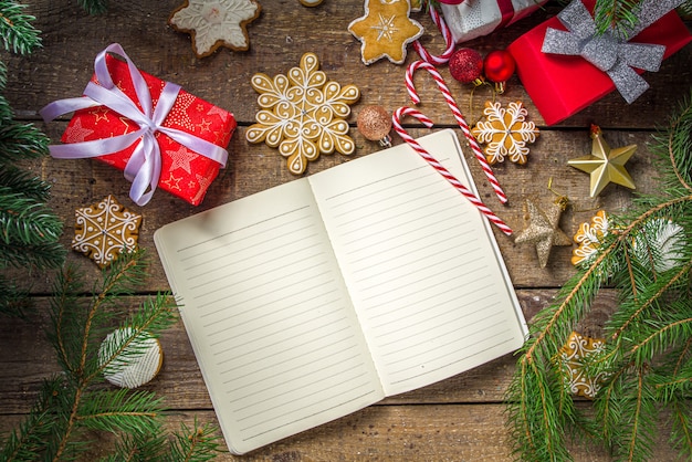 Regalos de Navidad con ramas de árboles y galletas de jengibre junto al cuaderno vacío