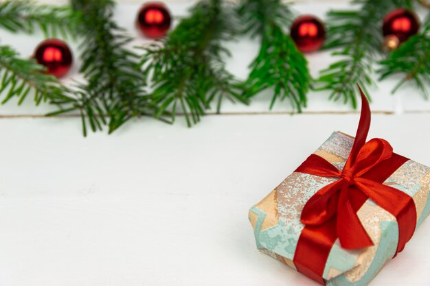 Regalos de Navidad con una ramita de abeto y decoraciones sobre un fondo de madera blanco