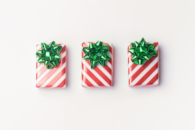 Regalos de Navidad y regalos de Año Nuevo en papel de regalo de rayas rojas con lazos verdes sobre fondo blanco
