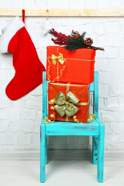 Regalos de Navidad en silla azul sobre la superficie de la pared de ladrillo