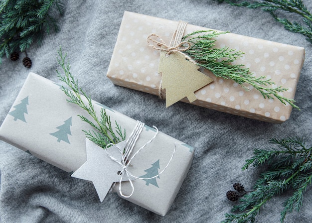 Regalos de Navidad sobre fondo gris textil tejido. Cajas de regalo de papel kraft, composición de Navidad y feliz año nuevo. Estilo plano, vista superior