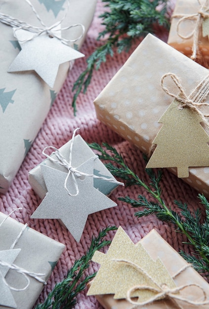 Regalos de Navidad sobre fondo rosa textil tejido. Cajas de regalo de papel kraft, composición de Navidad y feliz año nuevo. Estilo plano, vista superior
