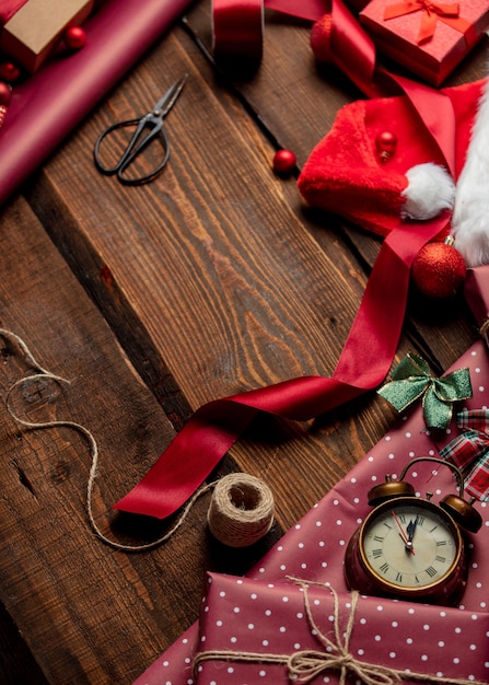 Regalos y papel rojo en tiempo de envoltura en mesa de madera