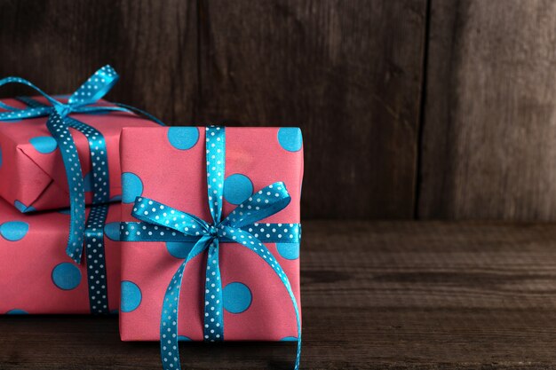 Regalos rosados con cinta azul en una estantería de madera vieja.