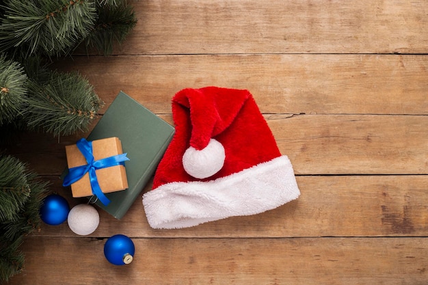 Regalos de sombrero de Santa Claus y ramas de un árbol de Navidad sobre un fondo de madera Vista superior plana