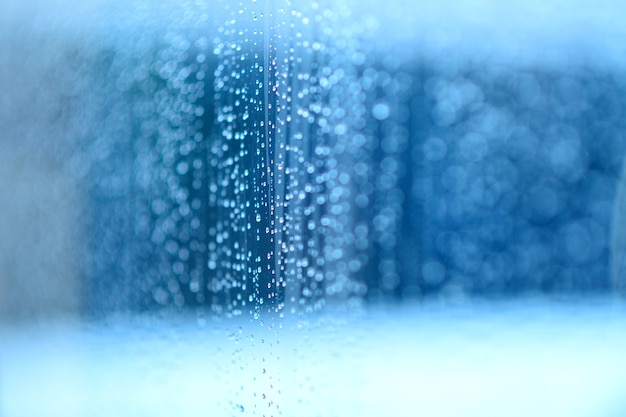 Regen fällt auf das Glas / blauer Hintergrund.