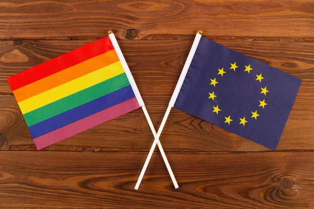 Regenbogen-LGBT-Flagge und Flagge der Europäischen Union EU auf braunen Holzplatten Hintergrund LGBT-Pride-Monat