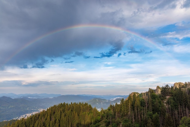 Regenbogen mit Farben an einem bewölkten Himmel über einem Tal der Rhodopen