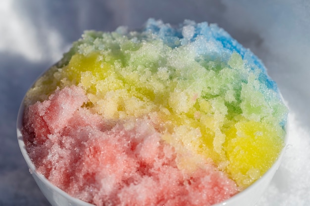 Regenbogen rasiertes Eis in Dessertschale auf weißem Schneehintergrund im Winter, Nahaufnahme