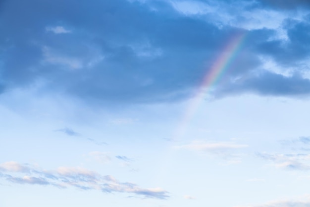 Regenbogen unter regnerischen Wolken am blauen Abendhimmel