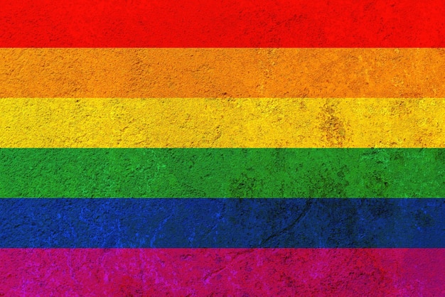 Regenbogenfahne gegen eine rostige Eisenwand. LGBT-Flagge auf eine rostige Eisenwand gemalt