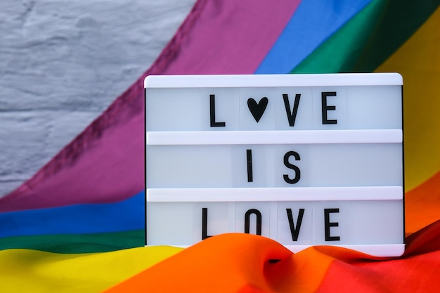 Foto regenbogenfahne mit lightbox und text liebe ist liebe regenbogen-lgbtq-flagge aus seidenmaterial symbol o