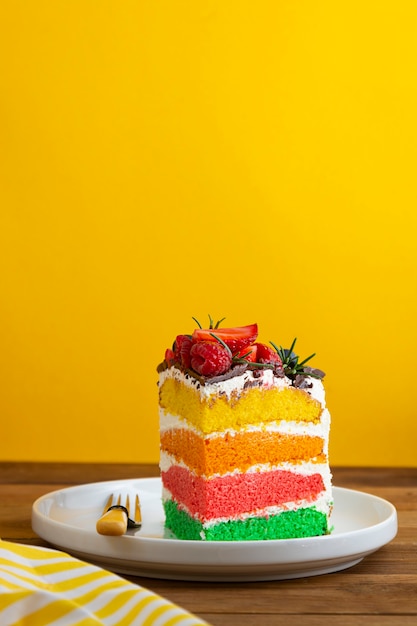 Regenbogenkuchen mit frischen Beeren auf gelbem Hintergrund