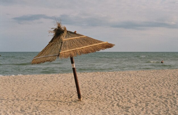 Regenschirm an einem Sandstrand gegen das Meer.