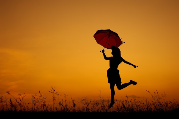 Regenschirm Frau springen und Sonnenuntergang Silhouette