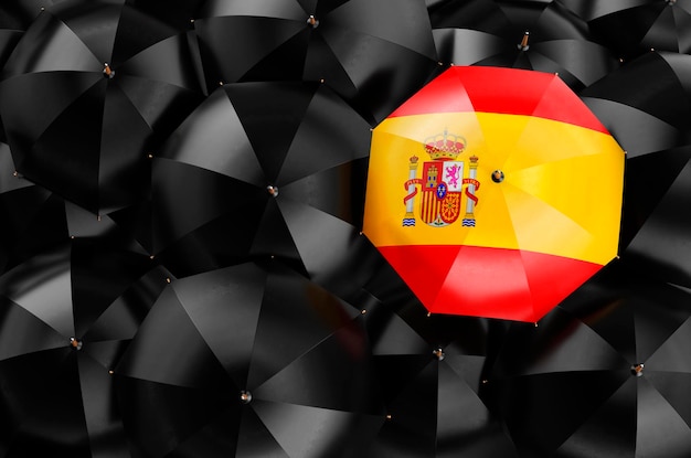 Foto regenschirm mit spanischer flagge unter schwarzen regenschirmen 3d-rendering