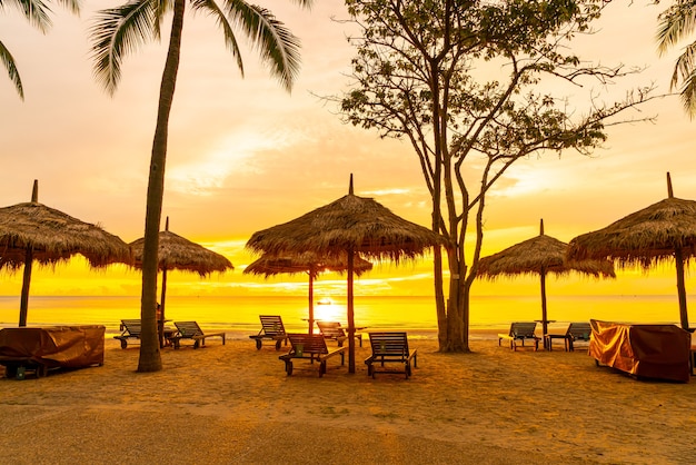 Regenschirm und Stuhl am tropischen Strand mit Sonnenaufgang am Morgen