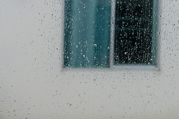 Regentropfen auf dem Fenster des Haushintergrundes