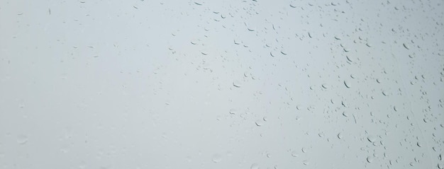 Regentropfen auf dem Fenster gegen grauen Himmel
