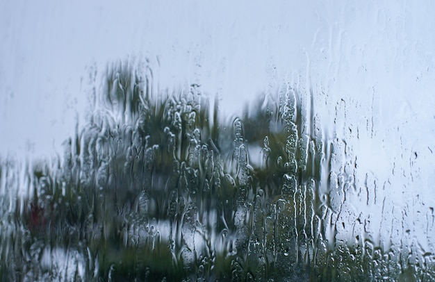 Regentropfen auf Fensterglasoberfläche mit Bokeh-Hintergrund.